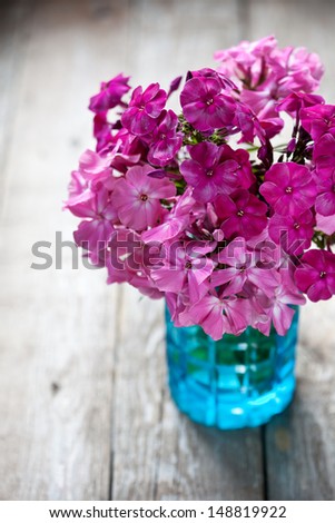 Pink flowers in vase on wooden background