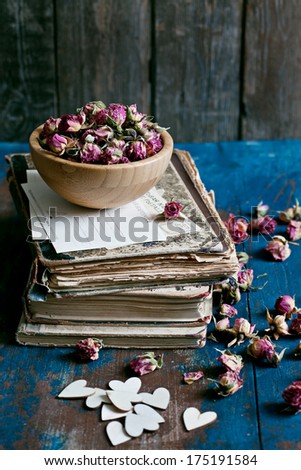 Dry roses in a wooden bowl, old books and vintage postcards.  Inscriptions on cards in Russian: postcard.