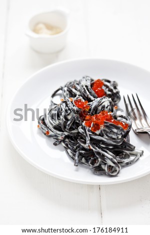 Black pasta with cream sauce and red caviar