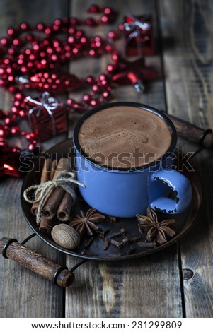 Hot chocolate with spices and christmas decoration on wooden background