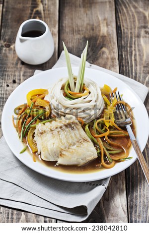 Fish with noodles and vegetables on wooden background