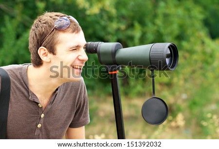 Man who is watching in spotting scope. Positive man looking through a telescope.