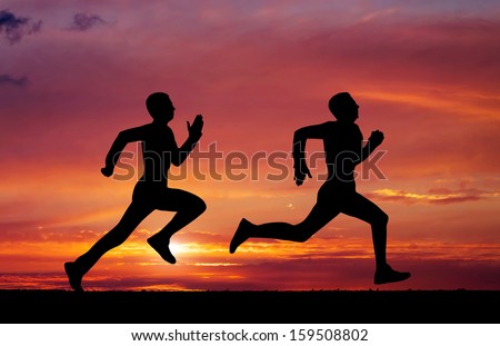 Silhouettes of two runners on sunset fiery background