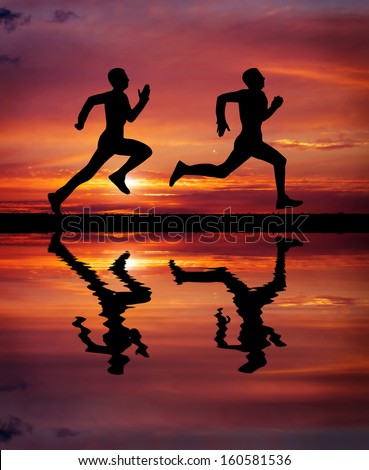 Silhouettes of two runners on sunset fiery background. Water reflection. Element of design.