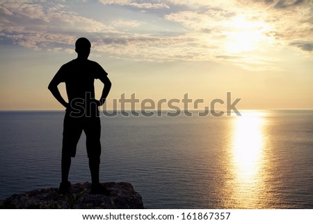 Silhouette of man on rock at sunset. Man on top of mountain. Conceptual design.