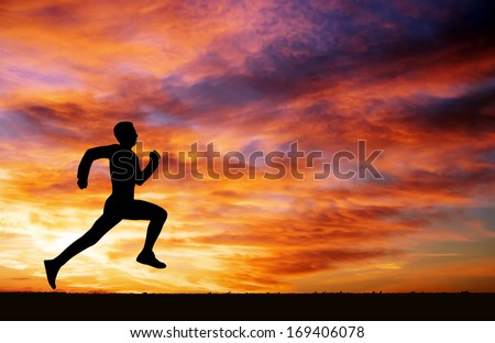 Silhouette Of Running Man Against The Colorful Sky. Silhouette Of Running Man On Sunset Fiery Background