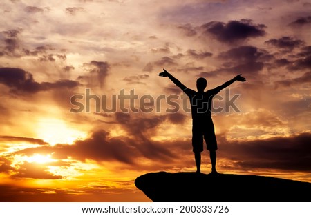 Silhouette of a man on a mountain top on fiery orange background