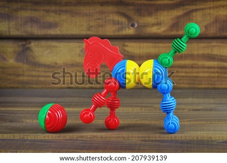 Toy horse and ball made from plastic colorful details on wooden background. Horse play with a ball.