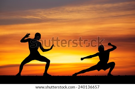 Silhouettes of two fighters on sunset fiery background