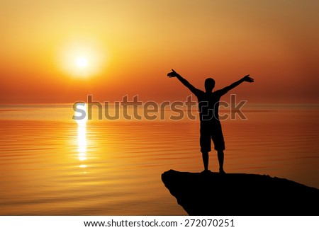 Silhouette of a man on a mountain top on sunset background