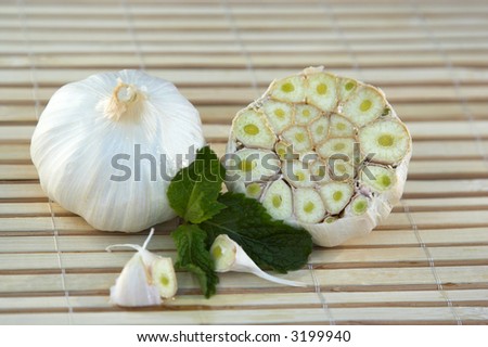Raw garlic cloves. Image shows a cross section of the cloves. Mint leaves are used as garnish