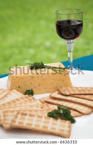 Smoked pike terrine with melba toast and parsley and chives as garnishing on a white platter. There is a glass of red wine in the background