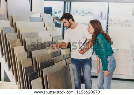 Couple looking ceramic and tiles for their new home floor. They are choosing in furnitures store