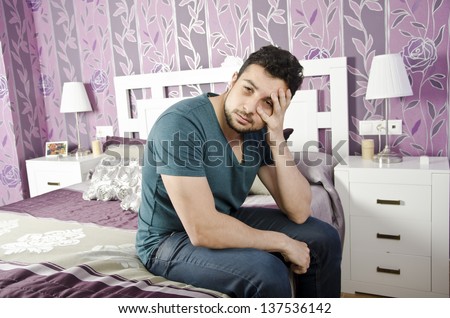 A man exhausted with eye circles in vintage bedroom.