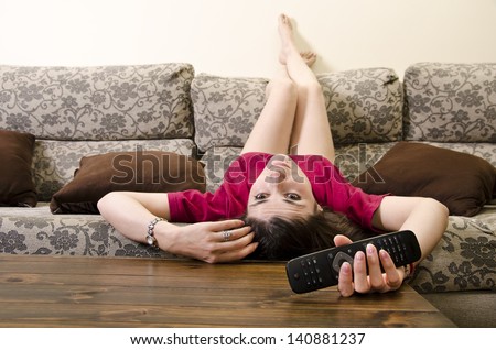 Girl lying face down watching television alone.