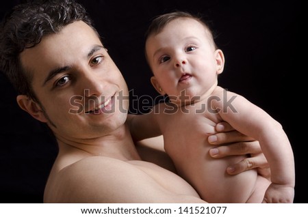 Dad and baby on dark background. Formal portrait.