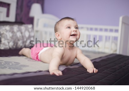 Happy Baby On A Bed, Lying And Smiling.
