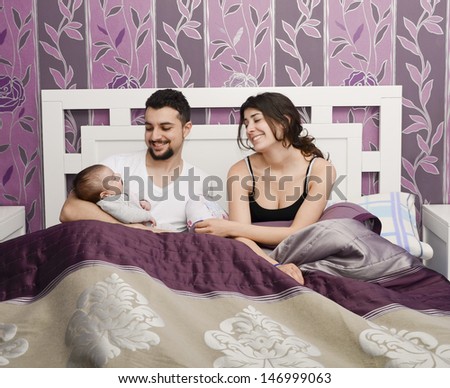 Happy parents in bedroom with baby in vintage bedroom.
