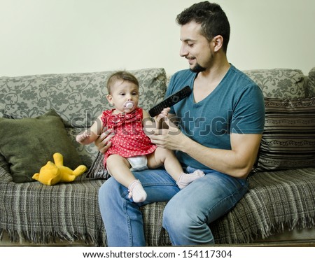 Father and baby in home bedroom watchching TV