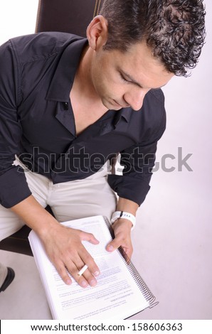 Man studying a script or studying a subject sitting in a chair.