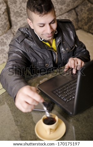 Young guy with pc writing  and searching in the net at home.