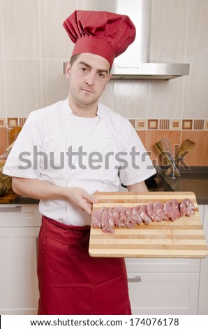 The chef in the kitchen. sliced meat n cutting board.