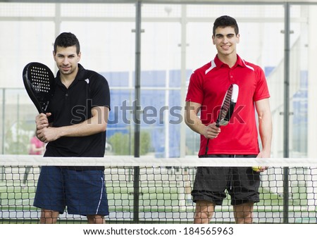 Paddle tennis team posing near to the net smiling