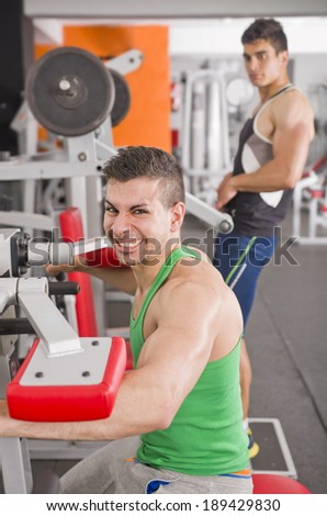 Two guys lifting weights in gym, shoulders exercises
