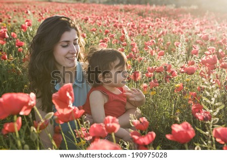 baby with his mother enjoying a field day outdoors, smiling in sunset back light