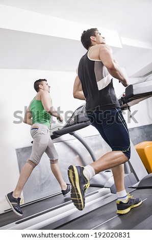 Two man in gym running on treadmill
