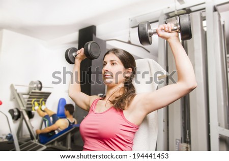Woman doing shoulder exercise with gym dumbbells