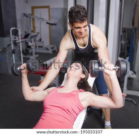 Man helping girl shoulders exercises at old gym