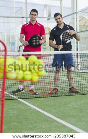 Paddle tennis couple ready for training paddle tennis classes with basket with balls