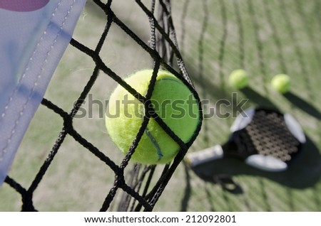 Paddle tennis shot on net, objects like racket and balls in the background, blurred. Action sports image.