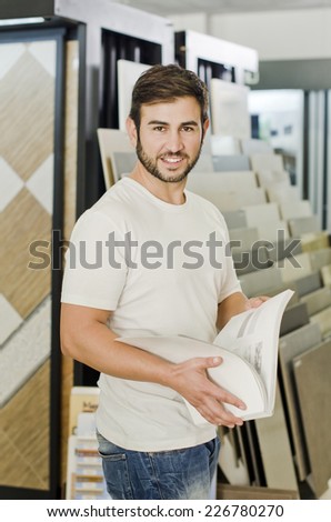 Plumbing, tile, ceramic and furniture store owner, clerk or client posing and smiling looking at the view with catalog.
