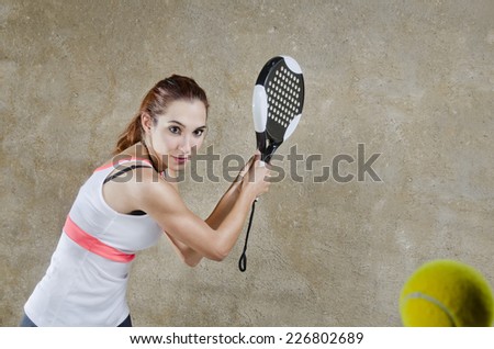 Young brunette woman in concrete paddle tennis court ready for backhand shot