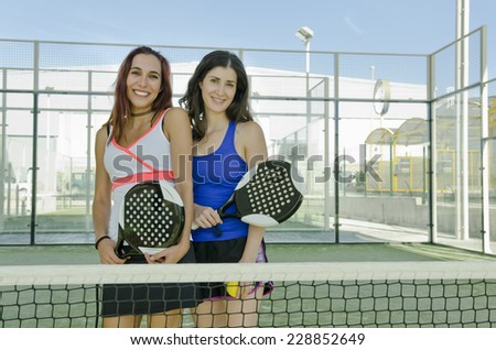 Two woman posing on paddle tennis court