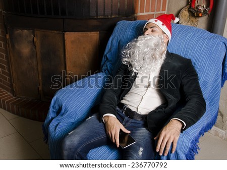 Young man with Santa Claus costume sleeping with possible hangover at sofa before christmas party