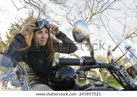 Smiling biker woman looking at mirror driving custom bike