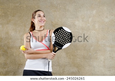 Smiling padde tennis woman posing on concrete wall