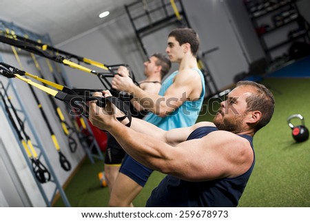Real people training cross fit and elastic rope at gym center