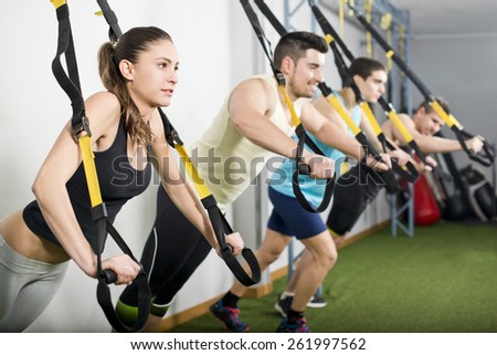 People at gym doing elastic rope exercises at cross fit room