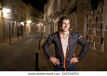 Young man smiling in sportswear posing in the street smiling, runner resting in street night.