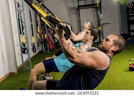 People training body suspension in elastic rope, three strong men