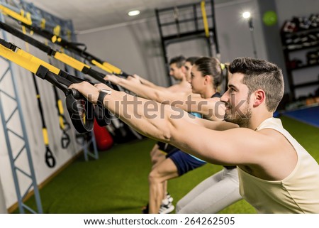 Group of people training in elastic rope at modern gym