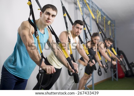 People at gym doing elastic rope exercises at crossfit room
