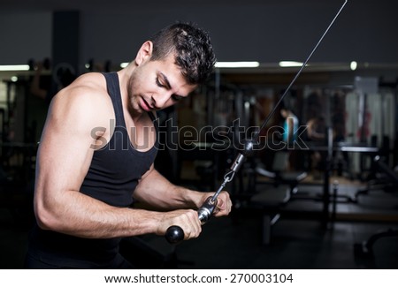 Young man training triceps at low key gym