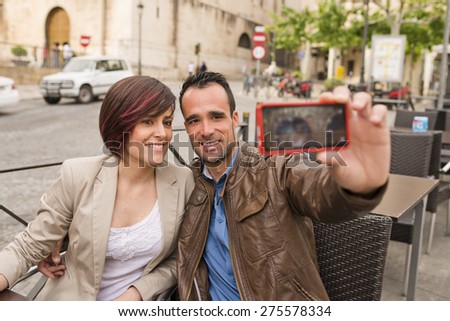 Couple in outdoors bar terrace with smartphone taking selfie with ambient light