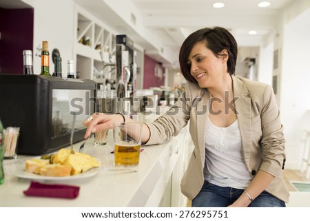 Woman in restaurant eating potato spanish omelet tapa with ambient light