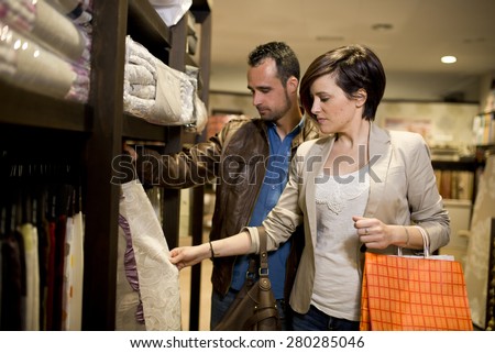 Shopping couple choosing cloths at home decoration store